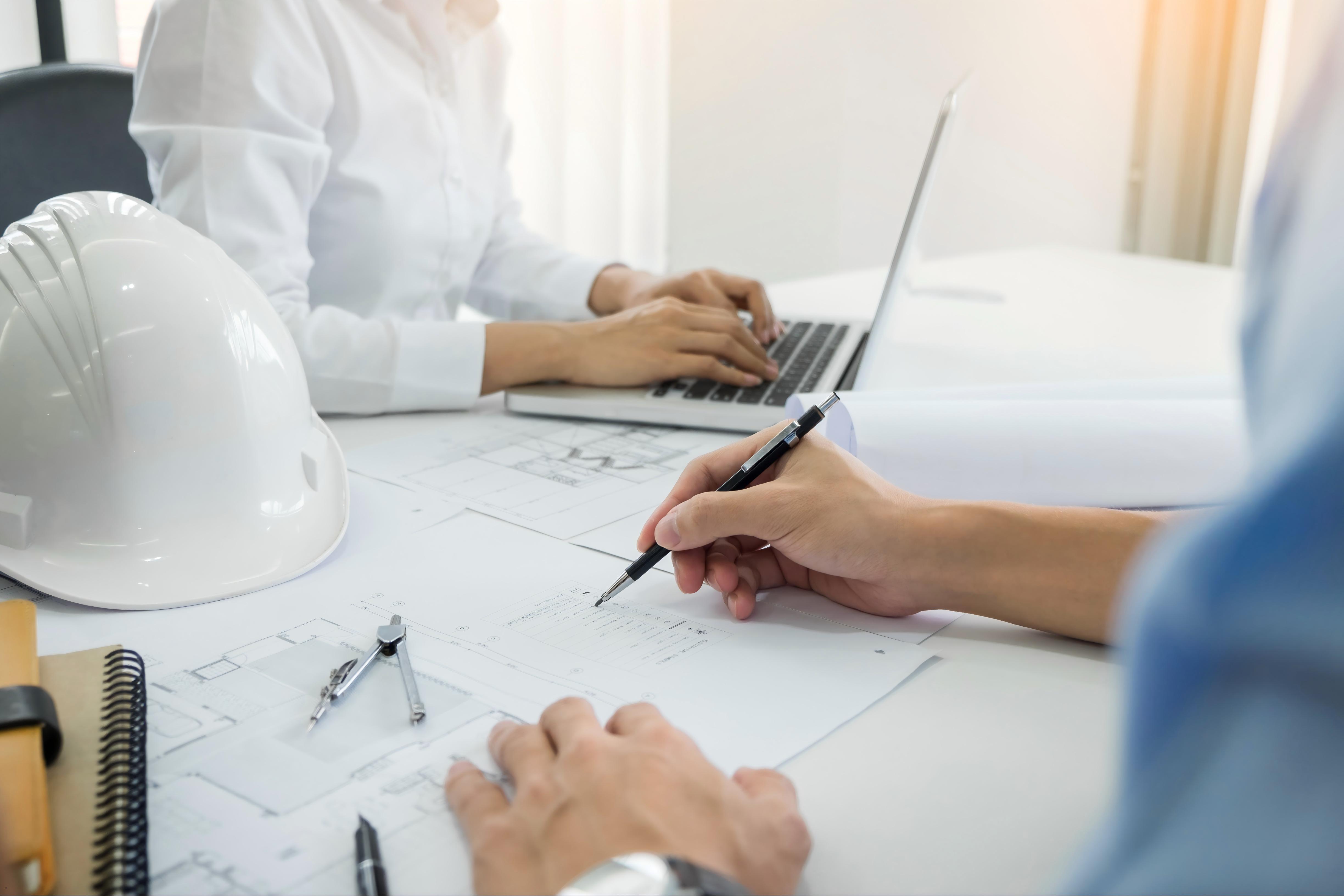 摄图网_302018419_建筑工程设计师在桌面上讨论蓝图手紧贴项目印刷品关于解构系统现场检查文件和业务工作流程问题（企业商用）(1)